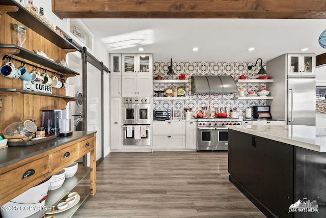 kitchen with high quality appliances, exhaust hood, a barn door, and open shelves