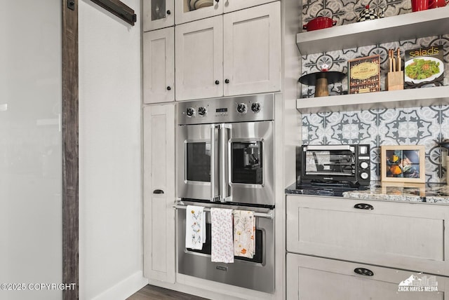 kitchen with double oven, stone countertops, and open shelves