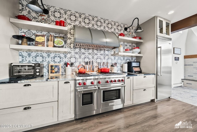 kitchen with open shelves, wood finished floors, ventilation hood, light stone countertops, and high end appliances