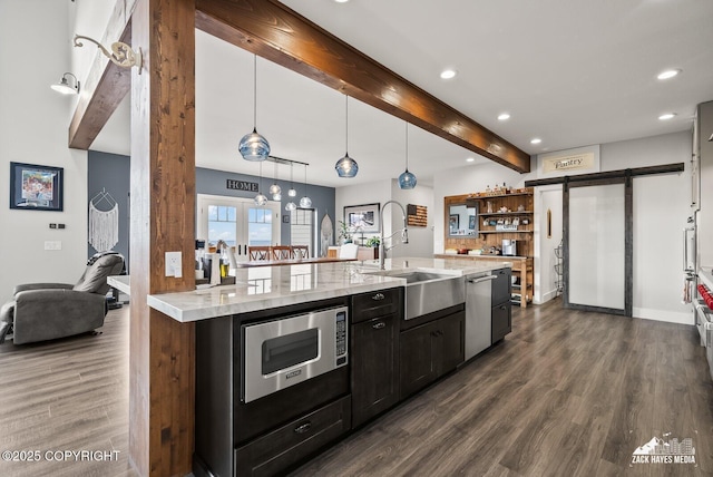 kitchen featuring stainless steel microwave, dark wood finished floors, beamed ceiling, a barn door, and a sink