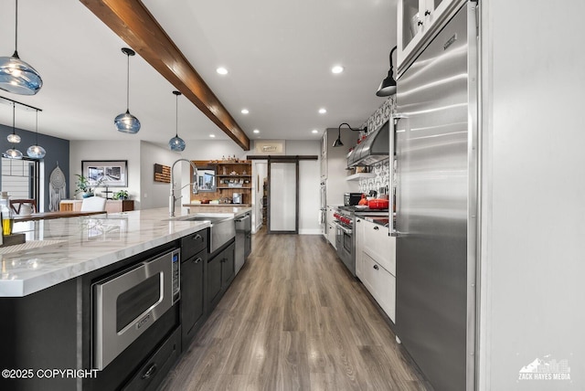 kitchen with beam ceiling, open shelves, wood finished floors, recessed lighting, and built in appliances