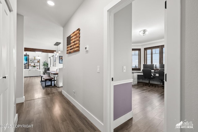 hallway featuring a chandelier, baseboards, dark wood-style floors, and ornamental molding