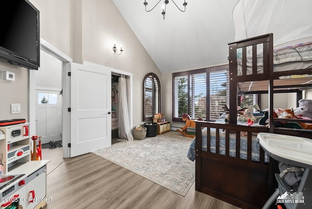 bedroom with multiple windows, light wood finished floors, and high vaulted ceiling