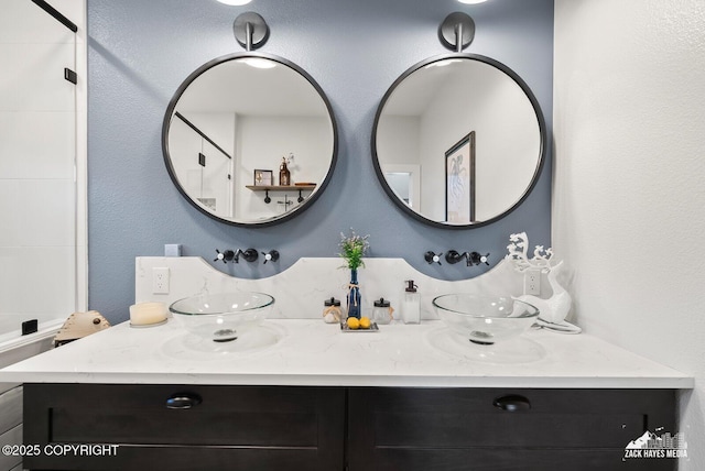 full bath featuring double vanity and a textured wall