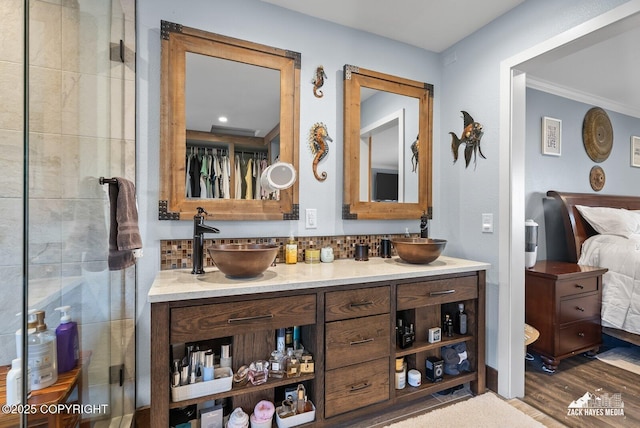 bathroom with double vanity, decorative backsplash, wood finished floors, and a sink