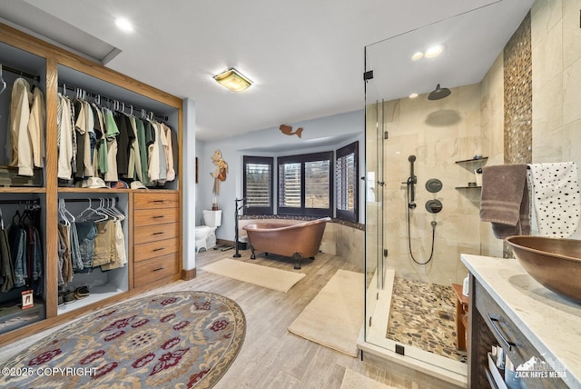 bathroom featuring a soaking tub, a stall shower, vanity, and wood finished floors