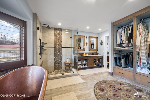 full bathroom with wood finished floors, a soaking tub, a stall shower, and vanity