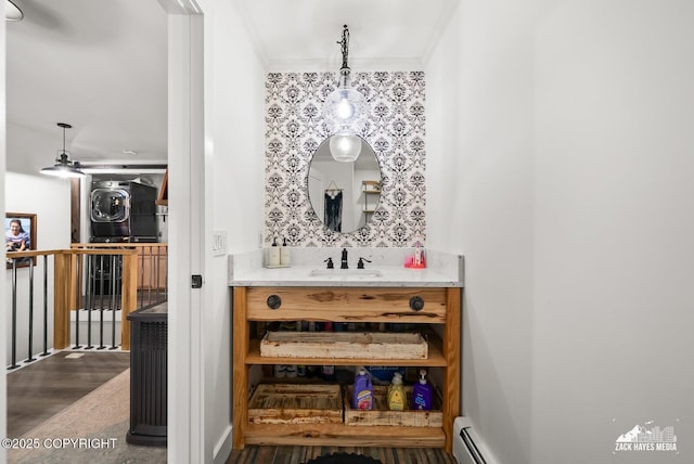 bathroom featuring a baseboard heating unit, wood finished floors, ornamental molding, and vanity