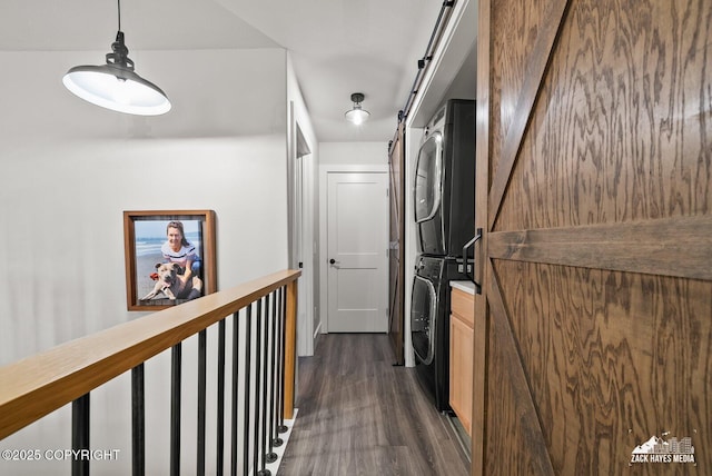 hall with dark wood-style floors, a barn door, and stacked washer and dryer