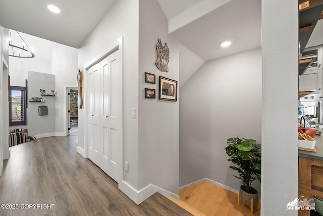 hallway featuring an inviting chandelier, wood finished floors, and baseboards