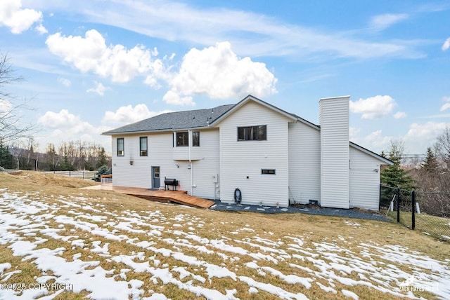 rear view of property with a chimney, a deck, and fence