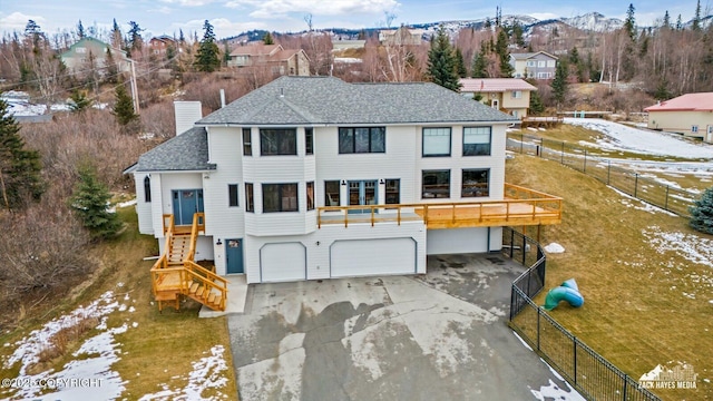 view of front facade with fence, stairs, a chimney, driveway, and an attached garage