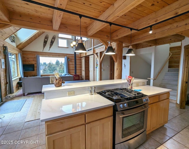 kitchen with stainless steel gas range oven, wood ceiling, open floor plan, light countertops, and an island with sink