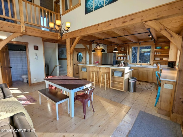 dining space featuring a chandelier, beam ceiling, light tile patterned flooring, and bar area