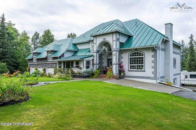 view of front of home with metal roof, a front lawn, a standing seam roof, and a chimney