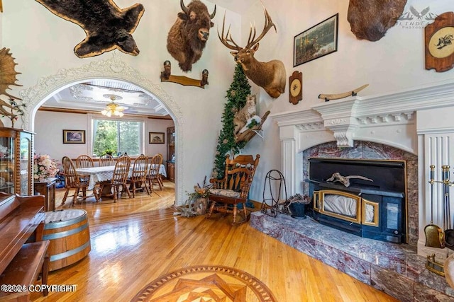 sitting room with arched walkways, ornamental molding, wood finished floors, and a high end fireplace