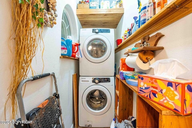 clothes washing area with stacked washer and clothes dryer and laundry area