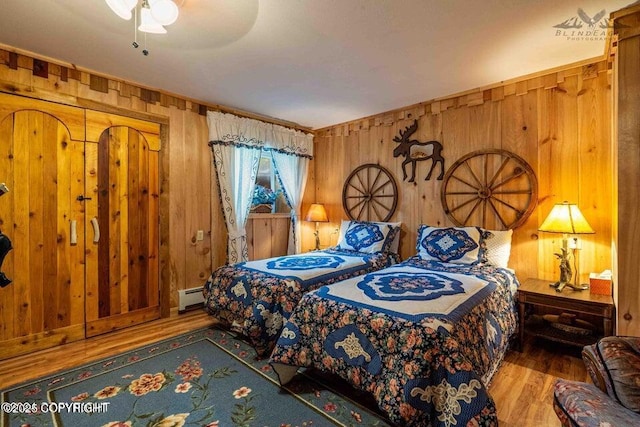 bedroom featuring a baseboard radiator, wooden walls, and wood finished floors