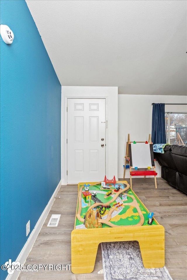 recreation room featuring visible vents, baseboards, and wood finished floors