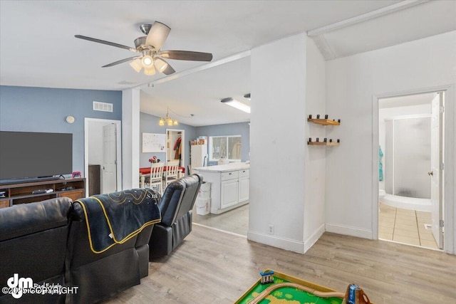 living room with lofted ceiling, ceiling fan with notable chandelier, visible vents, and light wood-style floors