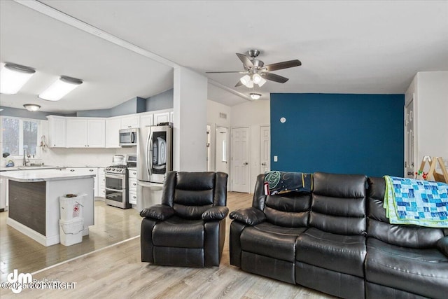 living room with light wood-type flooring, lofted ceiling, and ceiling fan