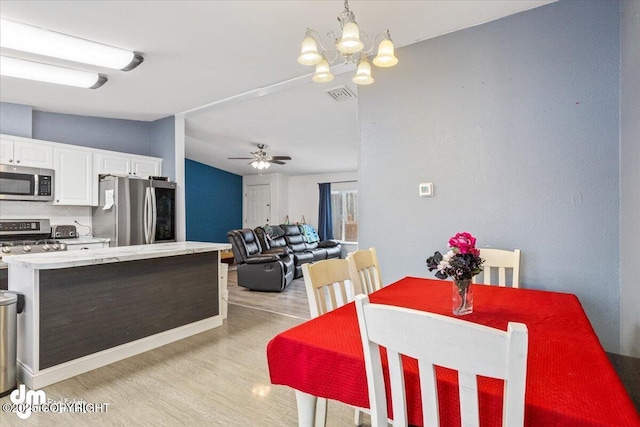 kitchen featuring white cabinets, appliances with stainless steel finishes, open floor plan, light countertops, and pendant lighting