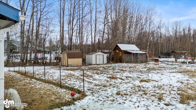 yard covered in snow featuring an outbuilding and a storage shed