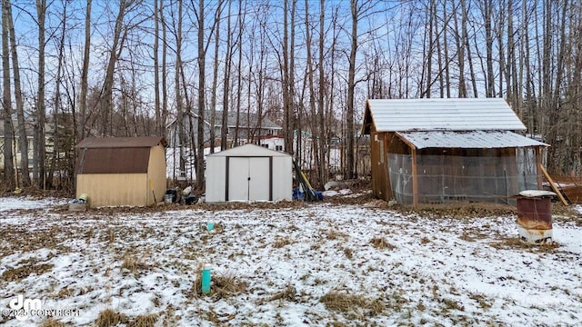 yard layered in snow with an outbuilding and a storage shed