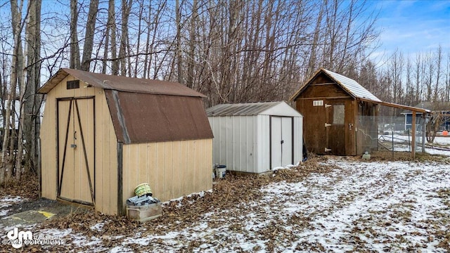 snow covered structure featuring an outbuilding and a storage unit