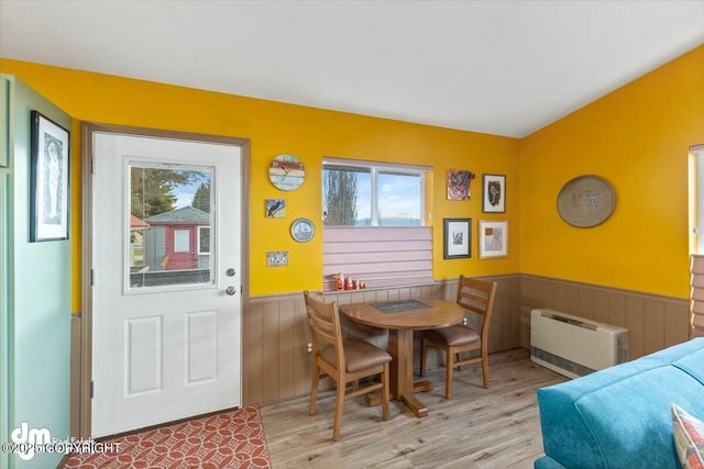 dining area with a wainscoted wall, light wood-type flooring, and heating unit