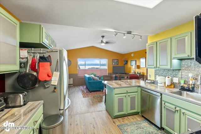 kitchen featuring green cabinetry, open floor plan, a peninsula, stainless steel appliances, and a sink