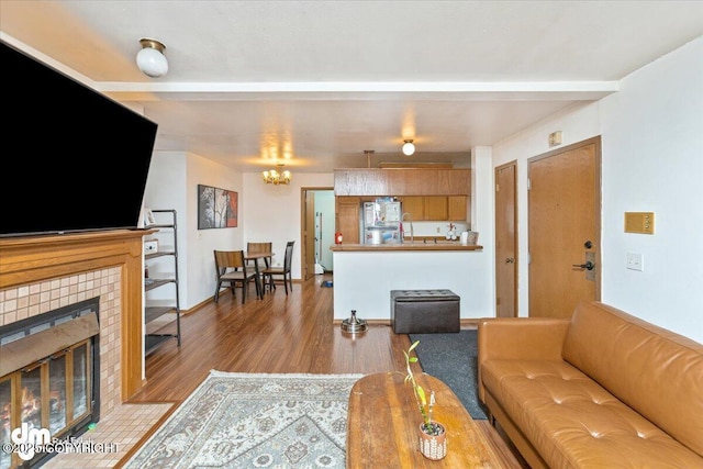 living area featuring a chandelier, a fireplace, beamed ceiling, and wood finished floors