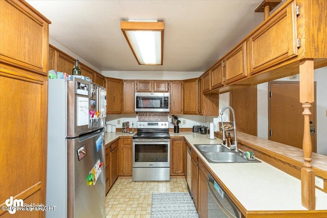 kitchen featuring appliances with stainless steel finishes, brown cabinets, light countertops, and a sink