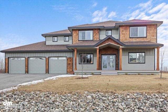 view of front of property featuring french doors, a shingled roof, board and batten siding, a garage, and driveway