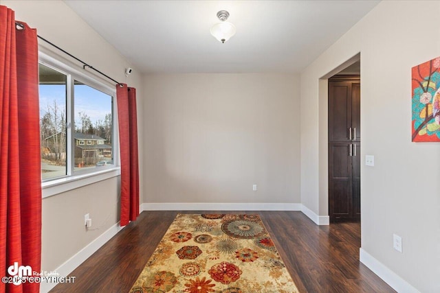 unfurnished room featuring dark wood-style floors and baseboards