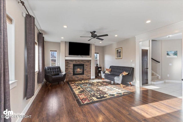 living room with recessed lighting, wood finished floors, a stone fireplace, and stairs