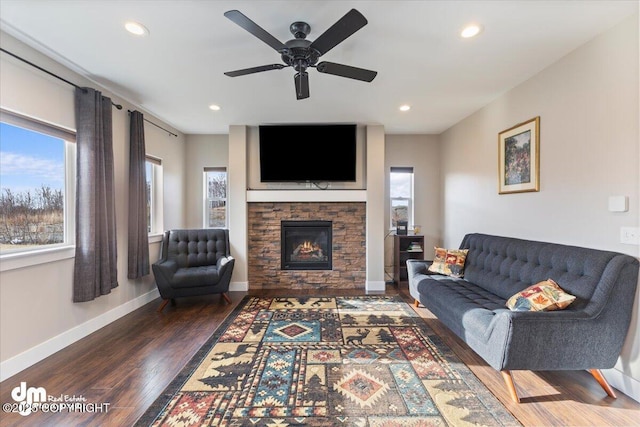 living room featuring a fireplace, baseboards, wood finished floors, and recessed lighting