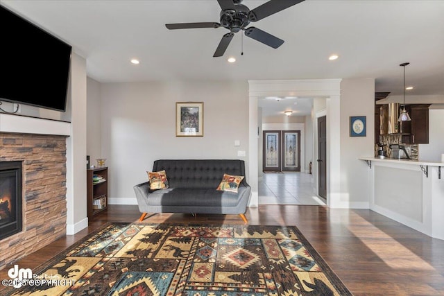 living room featuring a stone fireplace, wood finished floors, and recessed lighting