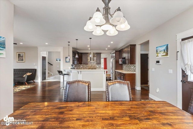 dining space with dark wood-style floors, recessed lighting, stairway, an inviting chandelier, and plenty of natural light