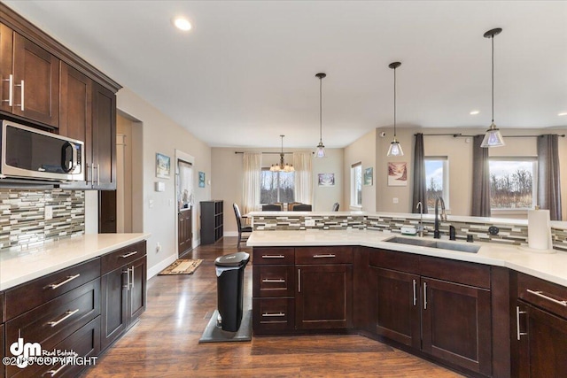 kitchen featuring light countertops, stainless steel microwave, a sink, and decorative backsplash