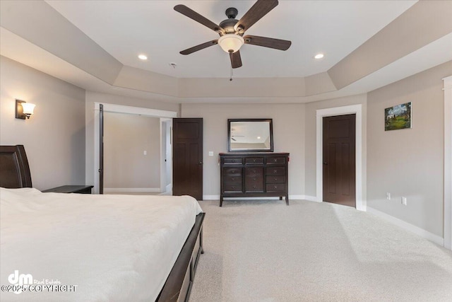 bedroom with a tray ceiling, light colored carpet, baseboards, and recessed lighting