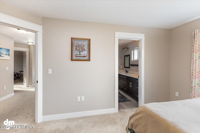 bedroom with light colored carpet, baseboards, and ensuite bathroom