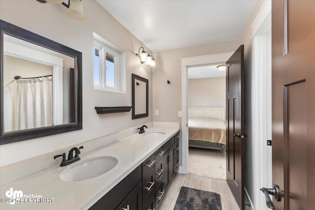 bathroom with double vanity, wood finished floors, ensuite bath, and a sink