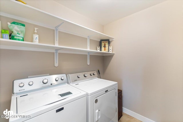 laundry area with laundry area, washing machine and dryer, and baseboards