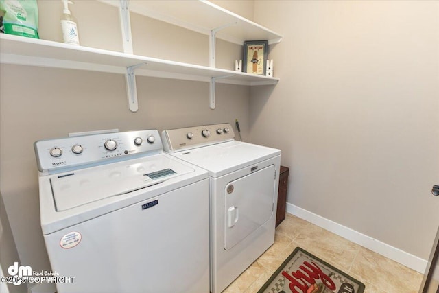 clothes washing area with washer and dryer, laundry area, baseboards, and light tile patterned floors