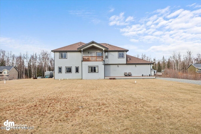 rear view of property with a balcony and a lawn