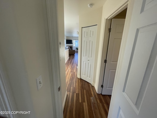 corridor with dark wood-type flooring and baseboards