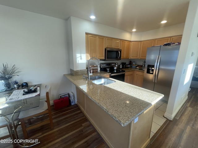 kitchen featuring light stone counters, appliances with stainless steel finishes, dark wood-type flooring, a sink, and a peninsula