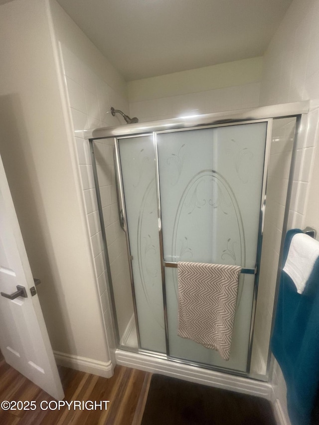 full bathroom featuring a stall shower and wood finished floors