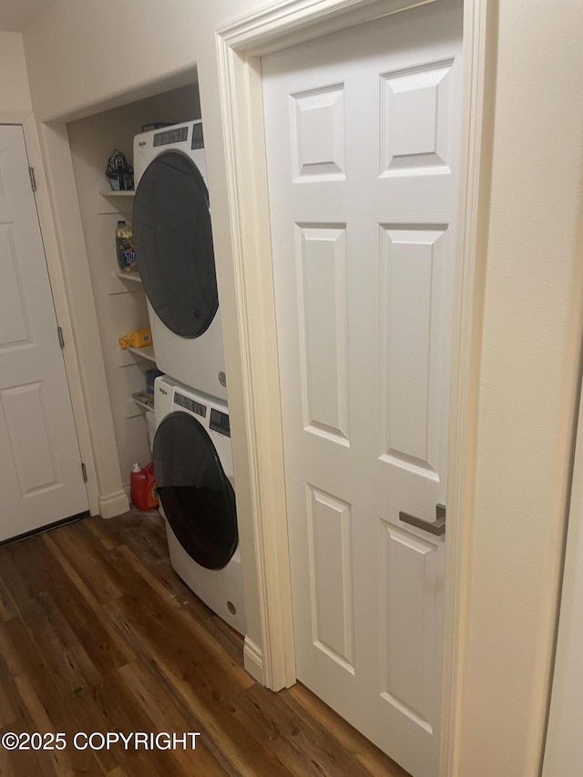 laundry area with stacked washer and dryer, dark wood-style floors, and laundry area